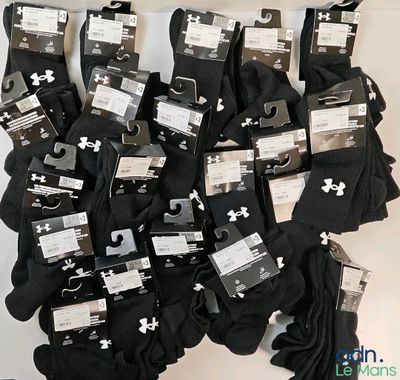 Plusieurs paires de chaussettes Under Armour noires et blanches sont exposées.