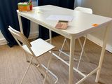 une table blanche avec deux chaises et un livre posé dessus