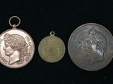 trois médailles d'argent et d'or posées les unes à côté des autres sur une surface noire