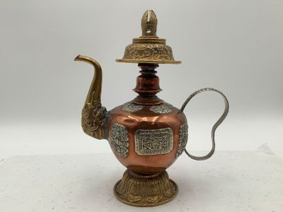 une théière ancienne en cuivre avec une poignée et un couvercle en laiton