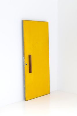 a yellow door with a brown handle in a white room