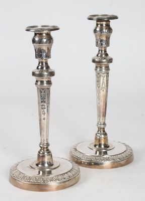 paire de bougeoirs en argent dont les socles sont ornés de motifs gravés