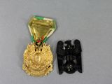 an image of a gold medal with a black eagle and a green ribbon