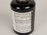 a close up of a bottle of black liquid on a white surface