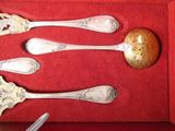 three silver spoons and a golden egg in a red box