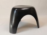 une image représentant un tabouret noir posé sur une table blanche