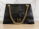 a black purse with a gold chain on a wooden table