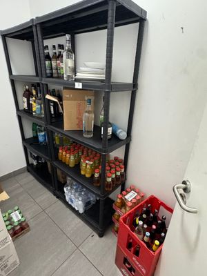 une étagère noire sur laquelle sont posées des bouteilles, dans un coin de la pièce
