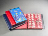 a red book with a blue cover sitting next to a stack of coins