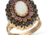 un gros plan d'une bague ornée d'une pierre blanche entourée de pierres violettes et noires