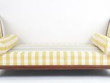 une chaise longue rayée jaune et blanche contre un mur blanc