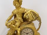gold colored clock sitting on top of a marble base with a statue of a woman holding a dog
