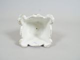 a small white vase that is sitting on a table