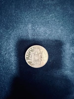 a small silver coin sitting on a black surface