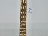 gros plan d'un bracelet en or sur une surface blanche
