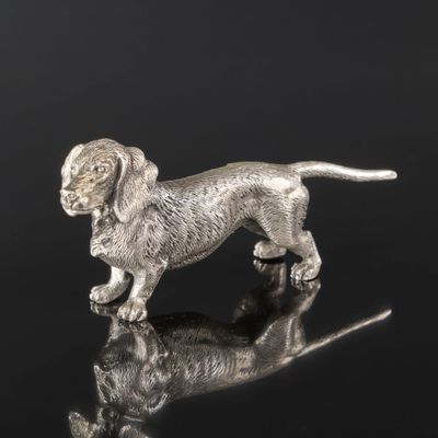 une figurine en argent représentant un chien posée sur une surface réfléchissante