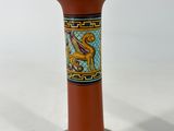 a red vase with a dragon on it sitting on a table
