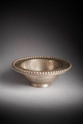 a silver bowl with a beaded rim on a gray surface