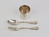 deux cuillères et une fourchette à côté d'une tasse en argent