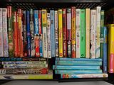 un panier en plastique noir rempli de livres et de DVD