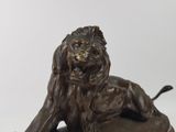 statue of a lion sitting on a rock on a white background