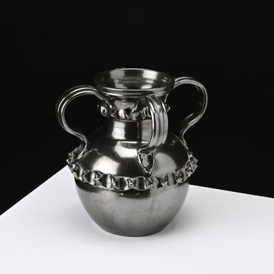 un vase en argent posé sur une table blanche
