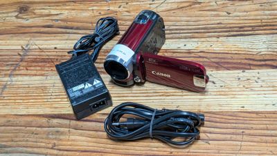 a red camera sitting on a wooden table with a charger