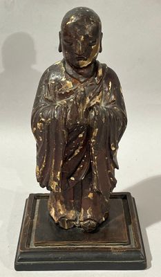 statue en bronze représentant une personne assise sur un socle, sur fond blanc