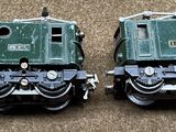 two green trains sitting side by side on the ground