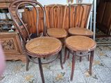 quatre chaises en bois placées les unes à côté des autres dans une pièce