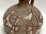 un vase brun orné d'un motif sur une surface blanche