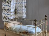 un petit lit surmonté d'un baldaquin, posé sur un plancher en bois
