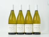 quatre bouteilles de vin sont alignées sur une surface blanche