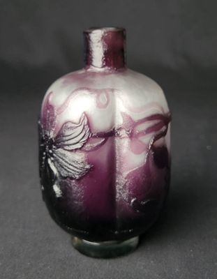 a purple vase with a bird on it on a black surface