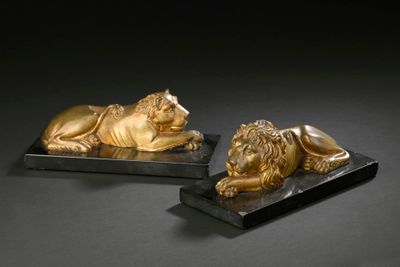 une paire de lions en bronze sur des socles en marbre noir