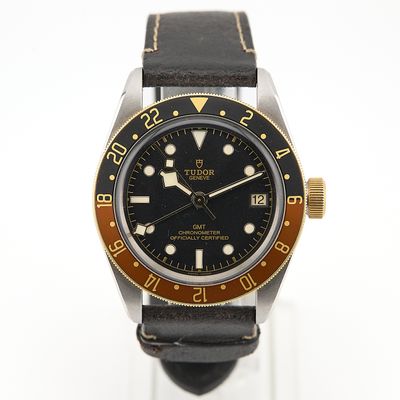 une montre noire et dorée montée sur un bracelet en cuir noir