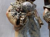 two figurines of a woman with a hat and holding flowers