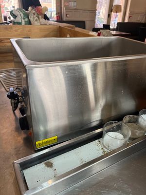 a stainless steel sink in a kitchen with a lot of bottles in it
