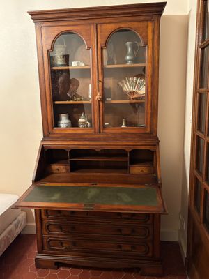 a wooden desk with a glass front cabinet in a room