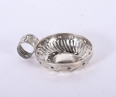 un petit bol en argent contenant une cuillère, posé sur une surface blanche