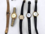 five watches and a pen on a table