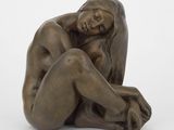 statue d'une femme assise à genoux sur une surface blanche