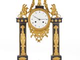 une horloge dorée et noire posée sur un socle orné de statues