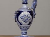 a blue and white vase with a ram head on it