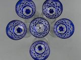 six blue glass bowls with silver rims are arranged in a circle