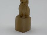 une statue représentant un chien assis sur un bloc de bois