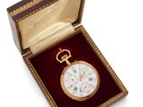 a gold pocket watch in a red box on a white surface