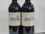 two bottles of red wine sitting on top of a white table