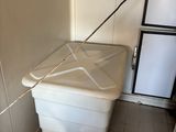 a white trash can in the corner of a room