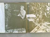 an old photo of a man sitting at a desk with a book open